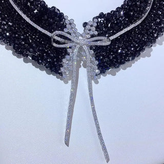 Black Onyx Bow Tie Necklace in sterling silver with lab sapphires, featuring a bow-shaped design and onyx center, displayed against a soft, neutral background