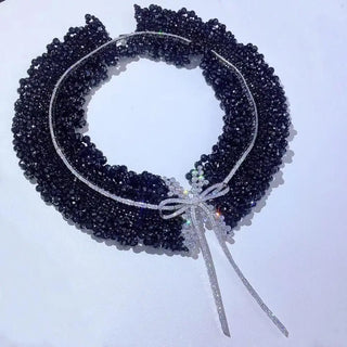 Black Onyx Bow Tie Necklace in sterling silver with lab sapphires, featuring a bow-shaped design and onyx center, displayed against a soft, neutral background