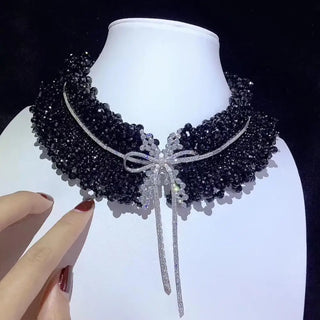 Black Onyx Bow Tie Necklace in sterling silver with lab sapphires, featuring a bow-shaped design and onyx center, displayed against a soft, neutral background