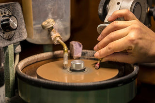 Skilled gem cutter working on a gemstone under magnification, illustrating how precise cuts enhance a gem’s brilliance, symmetry, and overall value.