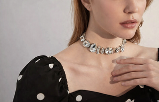 Model wearing a bold crystal statement choker necklace with oversized round and oval stones styled with a black polka dot dress.