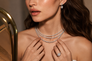 Close-up of a woman wearing layered diamond necklaces, diamond drop earrings, and a statement diamond ring, highlighting luxury fine jewelry and certified diamond craftsmanship.