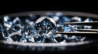 Multiple round brilliant diamonds arranged on a dark surface with tweezers holding one stone in focus
