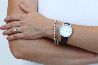 Woman’s wrist styled with a tennis bracelet and watch, showing how to layer jewelry for a chic and balanced look.