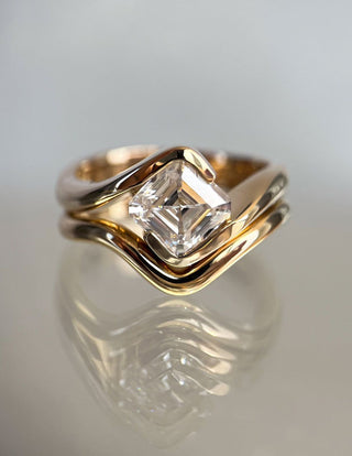 A hand gently cleaning a lab diamond ring with a soft cloth beside a jewelry cleaning kit on a marble surface.  