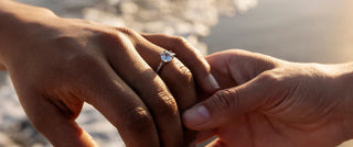 Close-up of a sparkling engagement ring placed next to a calculator and budget planner