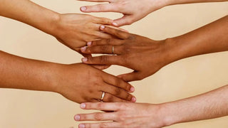 A woman comparing gold and silver jewelry against her wrist and neckline in natural light—demonstrating how different metal tones complement warm, cool, and neutral skin tones.