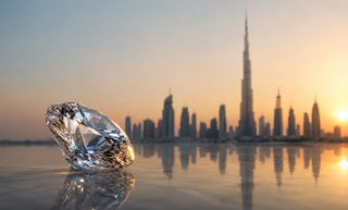 Large faceted diamond positioned against the Dubai skyline at sunset, with the Burj Khalifa and cityscape reflected across a polished surface.