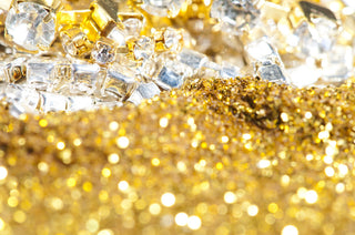 Gold bars stacked with loose cut diamonds in front, symbolizing the value debate between gold and lab-grown diamonds.