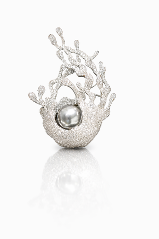 An ornate brooch with silver and white pearls, intricately designed to resemble branches, exuding elegance and charm.