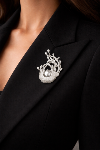  A professional woman dressed in a black suit, featuring a stylish brooch that adds a touch of sophistication.