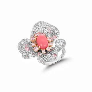 Floral cocktail ring in sterling silver featuring a central coral stone and pink lab sapphires arranged in a petal-inspired design.