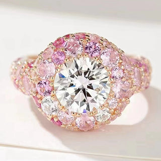 Close-up of a luxurious engagement ring featuring a large round brilliant-cut white gemstone at the center, surrounded by multiple pink and white sapphires set in a rose gold band.