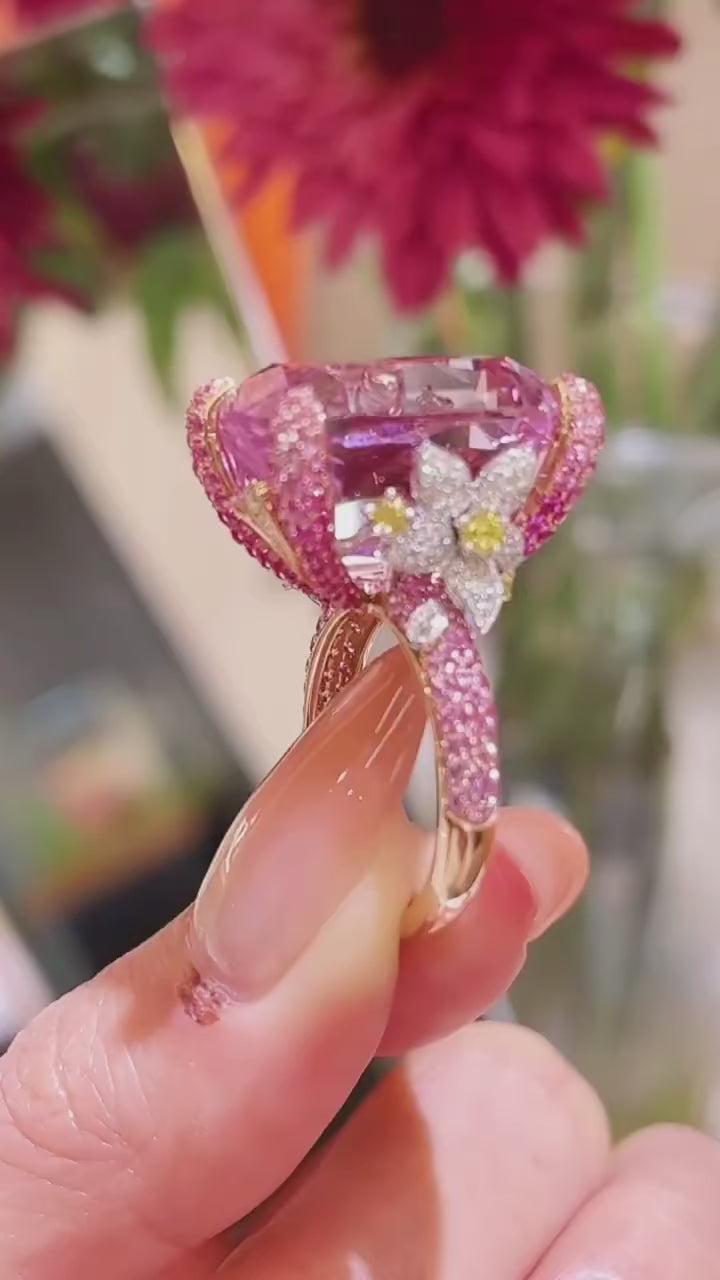 The Garden of Aurora Ring featuring an 8-carat pink lab-created sapphire in a rose gold setting, surrounded by sparkling lab sapphires. A symbol of love and new beginnings.

